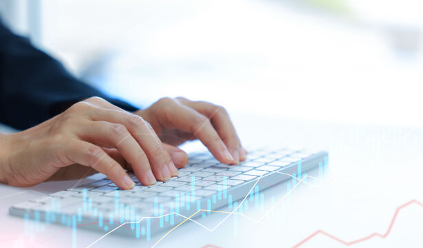 Close-up of hands typing on keyboard with financial stock chart overlay. Business data analysis, fintech, online trading, and digital technology concept in modern workspace.