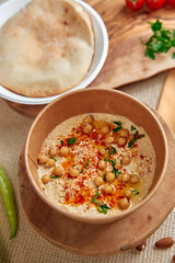 A Delicious Bowl of Creamy Chickpea Hummus Garnished with Spices, Nuts, and Fresh Herbs Served Alongside Soft Bread and Colorful Vegetables