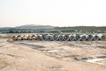 Expansive construction site with exposed earth and heavy machinery tracks. Surrounded by distant...