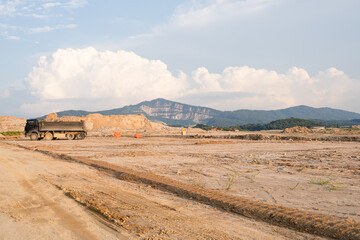 Expansive construction site with exposed earth and heavy machinery tracks. Surrounded by distant...