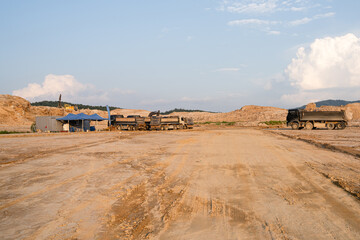 Expansive construction site with exposed earth and heavy machinery tracks. Surrounded by distant...