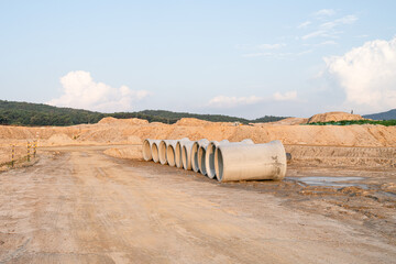Expansive construction site with exposed earth and heavy machinery tracks. Surrounded by distant...