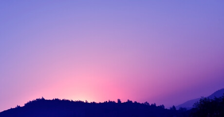 Purple golden yellow orange sky and white cumulus cloud with sunlight shining through mountain in...