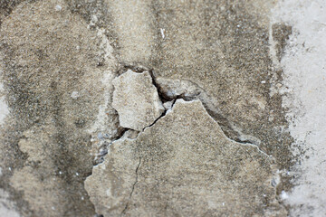 Close-up of cracked and peeling concrete wall surface, showing texture of deterioration and structural damage over time.