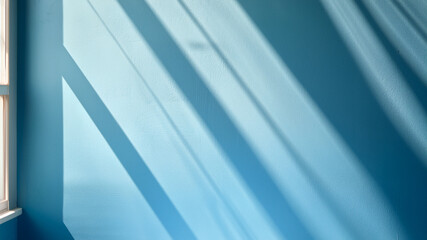 Sunlight casts dramatic shadows on a modern blue wall, creating a stylish abstract background.