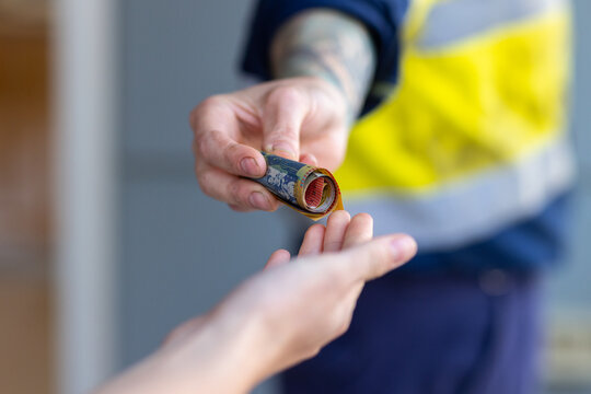 cash transaction with roll of Australian currency banknotes changing hands