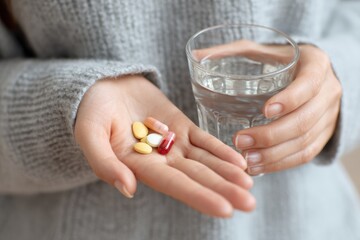 Hands holding medicine pills and a glass of water
