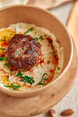 Deliciously Creamy Hummus Topped with Savory Spiced Meat, Garnished with Fresh Herbs and Drizzled with Olive Oil for an Irresistible Dish