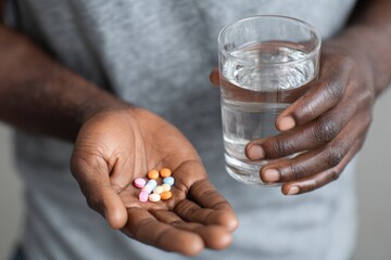 Hands holding medicine pills and a glass of water