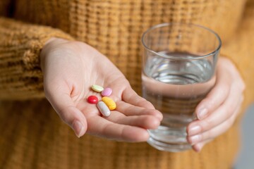 Hands holding medicine pills and a glass of water