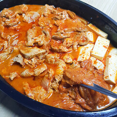 A close-up of kimchi jjigae, a hearty and spicy Korean kimchi stew, with tofu and pork.