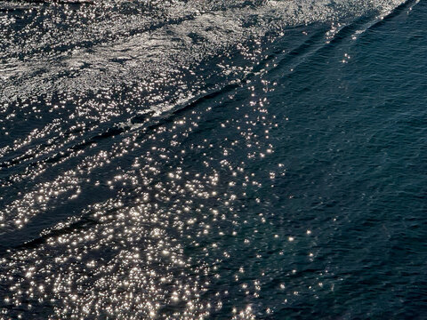 Glittering sea with sun sparkles on blue water surface.