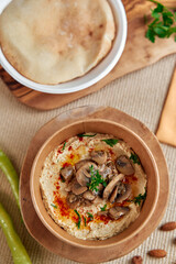 Delicious and Creamy Hummus Topped with Flavorful Mushrooms and Fresh Herbs Served with Soft Flatbread on a Rustic Wooden Table