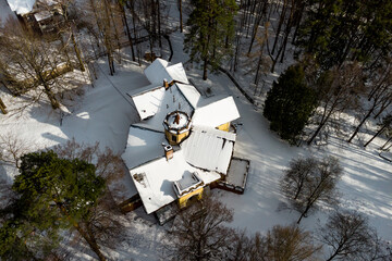 A century-old manor house covered in white snow standing surrounded by forest, aerial view