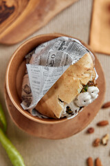 Freshly Made Wrap with Herb-Filled Ingredients Served in a Wooden Bowl, Perfectly Accompanied by Nuts and Herbs for a Delicious Snack