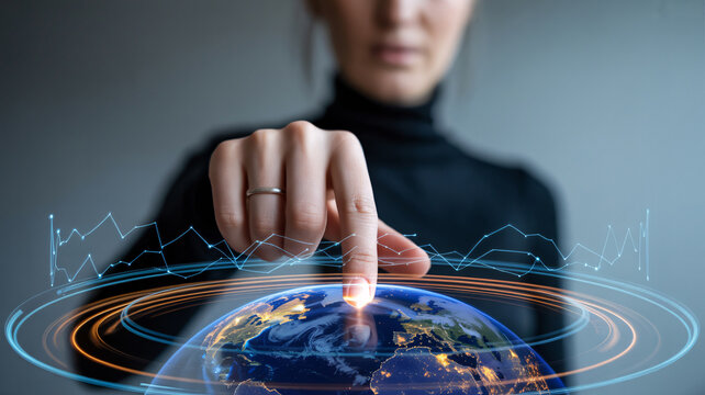 Woman's finger pointing at Earth hologram with financial graph overlay image photo