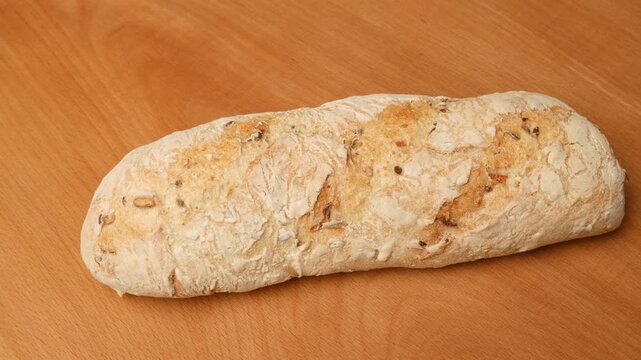 Rotating loaf of multigrain bread on wooden table