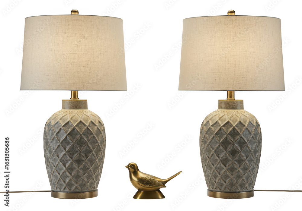 Poster a pair of decorative table lamps with textured bases and a small bronze bird figurine in between, is