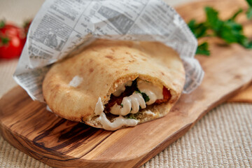 Deliciously Stuffed Pita Bread Filled with Fresh Ingredients and Creamy Sauce Served on a Wooden Board