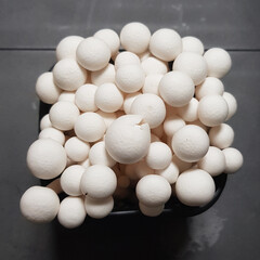 A close-up of a container of fresh white buna shimeji mushrooms, a wholesome and common ingredient...