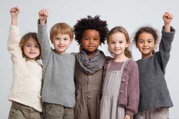 Diverse group of young children joyfully celebrate together while holding their fists up in excitement