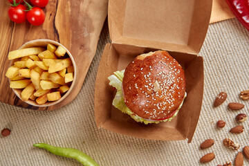 Delicious Hamburger with Fresh Ingredients Served Alongside Crispy French Fries and Cherry Tomatoes...