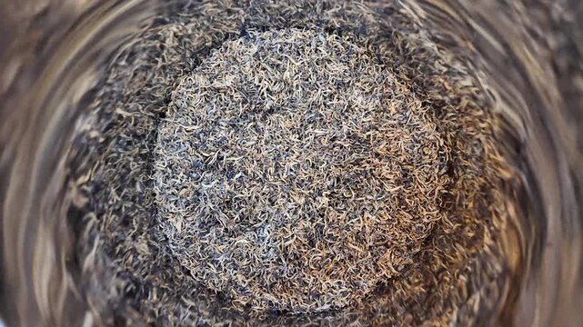 Dried golden needle tea heap in a stainless steel container.	