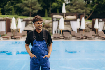 Pool maintenance worker standing near empty covered pool during summertime
