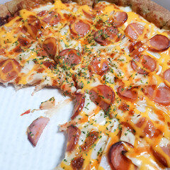 A close-up of a slice of pizza with various toppings, including cheese, sausages, and onions.