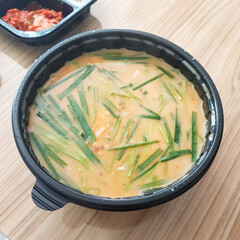 A close-up of a bowl of Korean rice soup (gukbap) with pork and vegetables, a savory and wholesome takeout meal.