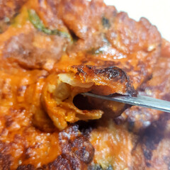 A close-up of a plate of spicy kimchi pancakes (kimchi-jeon), a savory and wholesome Korean side dish.