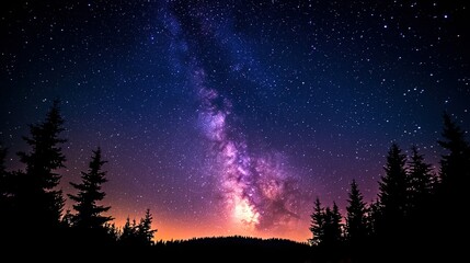 Naklejka premium Night sky with milky way visible above trees and horizon glow.