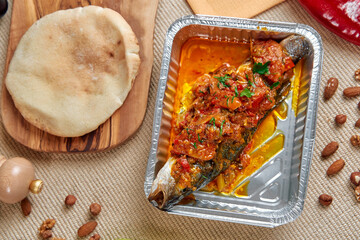 Delicious Grilled Fish Served With Spicy Tomato Sauce Accompanied By Warm Bread And Nuts, Ideal For A Flavorful Dining Experience.