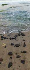 waves on the beach crashing against small rocks