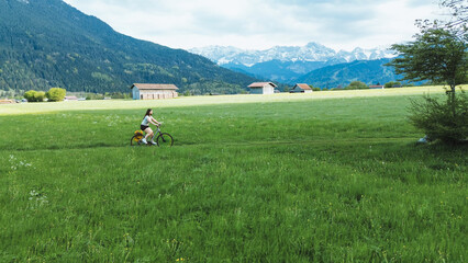 Active woman biking rural alpine valley