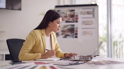 Asian woman architect diligently works on laptop creating innovative designs in modern office managing architectural projects for urban development and property success - Powered by Adobe