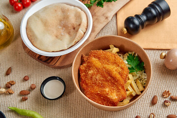 A Deliciously Plated Meal Featuring Crispy Chicken Cutlet, Fresh Vegetables, Pita Bread, and Tangy...