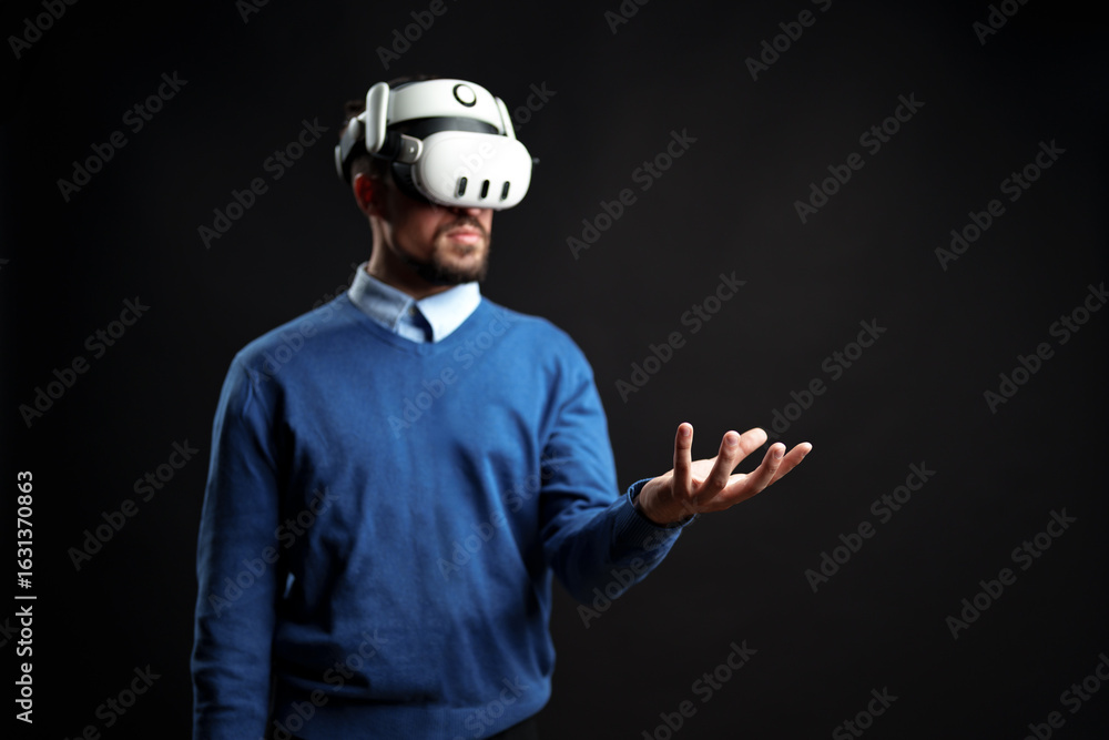 Poster man wearing virtual reality headset engages with digital environment in indoor studio setting