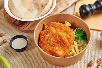 A Deliciously Prepared Crispy Fried Fish Fillet Served with Fresh Sides and Accompaniments in an Eco-Friendly Packaging Container