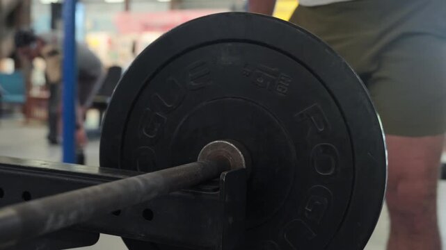 Standing Bent-over Barbell Row With Overhand Grip - Man Placing 15 Kg Weight Plates On The Barbell. - closeup shot