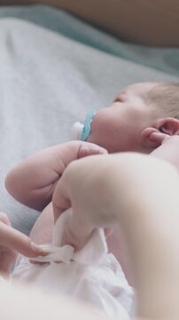 careful nurse hands treat lying infant with pacifier in mouth umbilical cord holding cotton pad close view