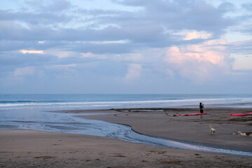 Peaceful morning atmosphere at Seminyak Beach, Bali, where soft waves meet wide stretches of sand under pastel skies, creating a serene coastal view with gentle colors and quiet reflections.
