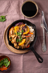 Asian pork with vegetables and glass noodles in a pan on the black background vertical photo