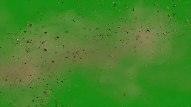 A powerful blast of dirt, dust, and debris erupting against a green screen, perfect for visual effects and chroma key compositing.