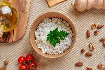 A Delicious Bowl of Steamed White Rice Garnished with Fresh Parsley, Surrounded by Cherry Tomatoes, Almonds, and Olive Oil on a Rustic Table Setting
