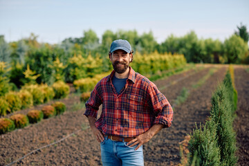 Fototapeta premium Happy plant nursery owner in field looking at camera.