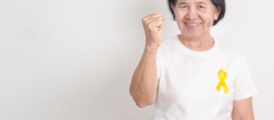 Elderly with Yellow Ribbon for concept of yellow September, Suicide prevention day, Childhood, July Sarcoma, bone and bladder cancer Awareness month, support survivor. Healthcare and World Cancer day