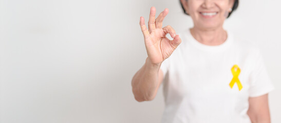 Elderly with Yellow Ribbon for concept of yellow September, Suicide prevention day, Childhood, July Sarcoma, bone and bladder cancer Awareness month, support survivor. Healthcare and World Cancer day