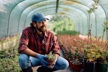 Happy worker at plant nursery looking away.