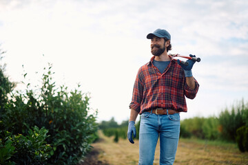 Portrait of happy farm worker with pruning scissors looking away.